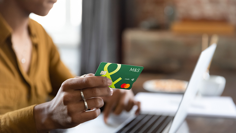 Close up of hand holding Credit Card over laptop