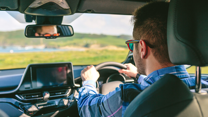 A man wearing sunglasses driving a car