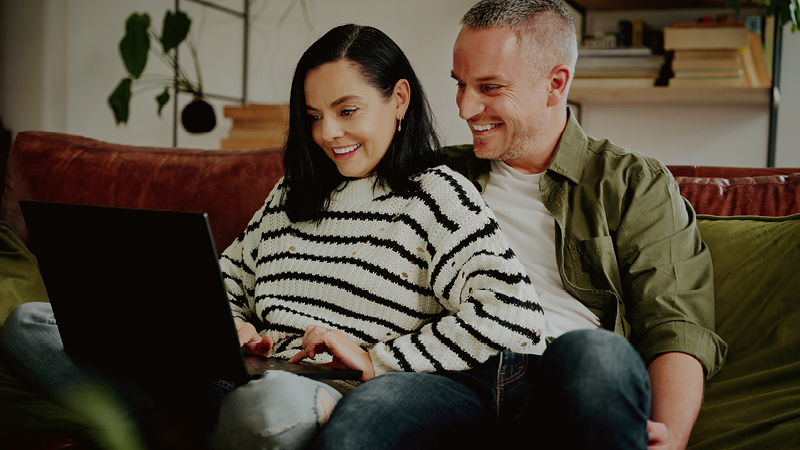 Couple sitting on couch with laptop