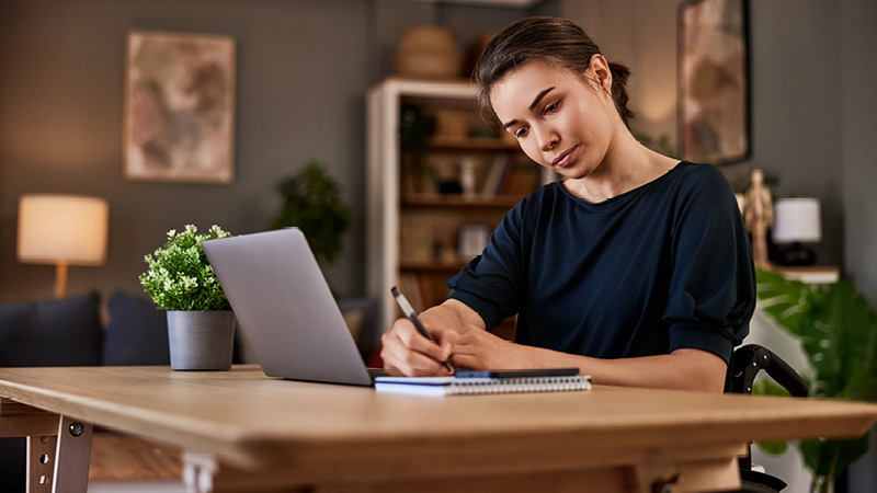 person in wheelchair at desk with tablet device