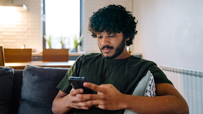 Man sitting on sofa using mobile phone
