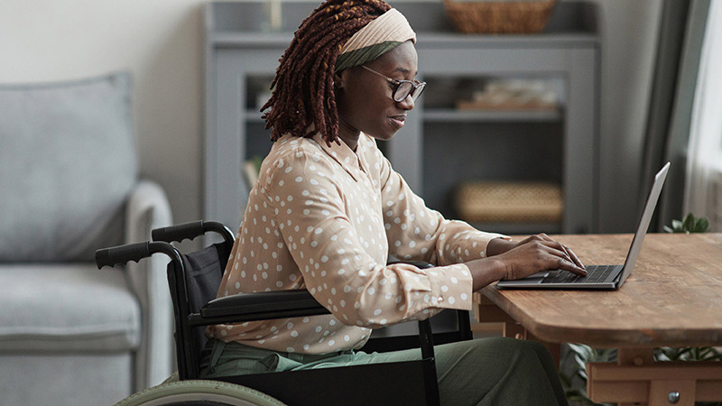 Person in wheelchair at table with laptop